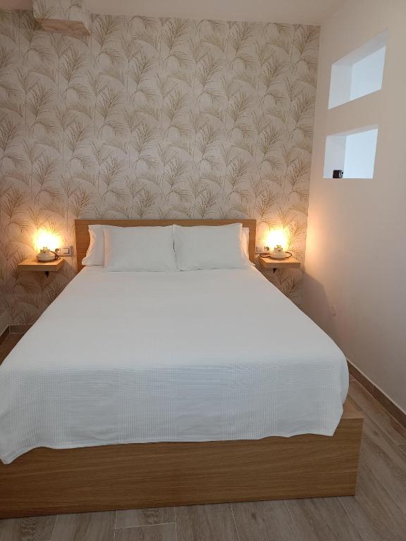 a bedroom with a large white bed with two lamps at La Lunita in Valverde