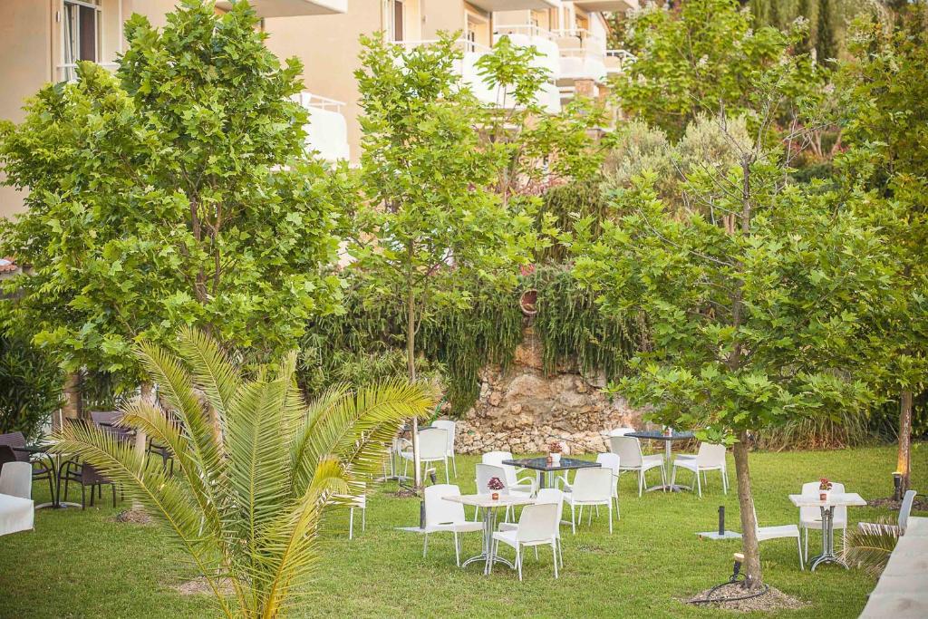 a group of tables and chairs in a yard with trees at Sunny Hill in Sani Beach