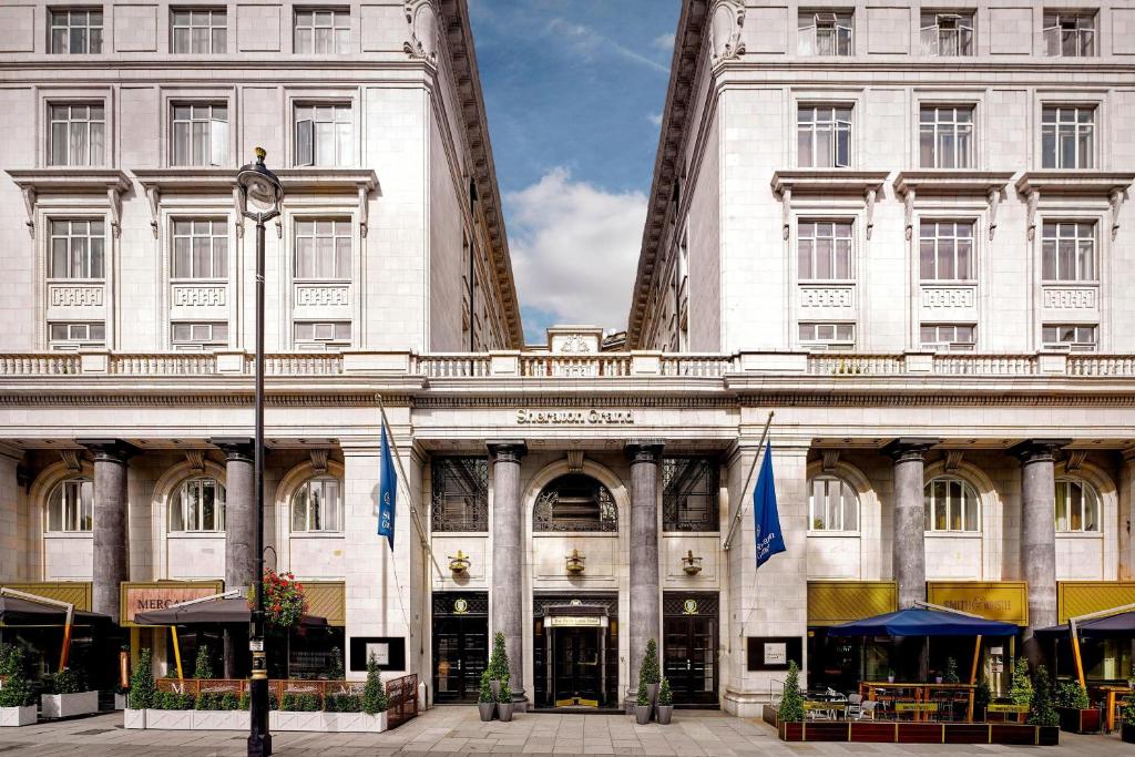 a large white building with blue flags in front of it at Sheraton Grand London Park Lane in London