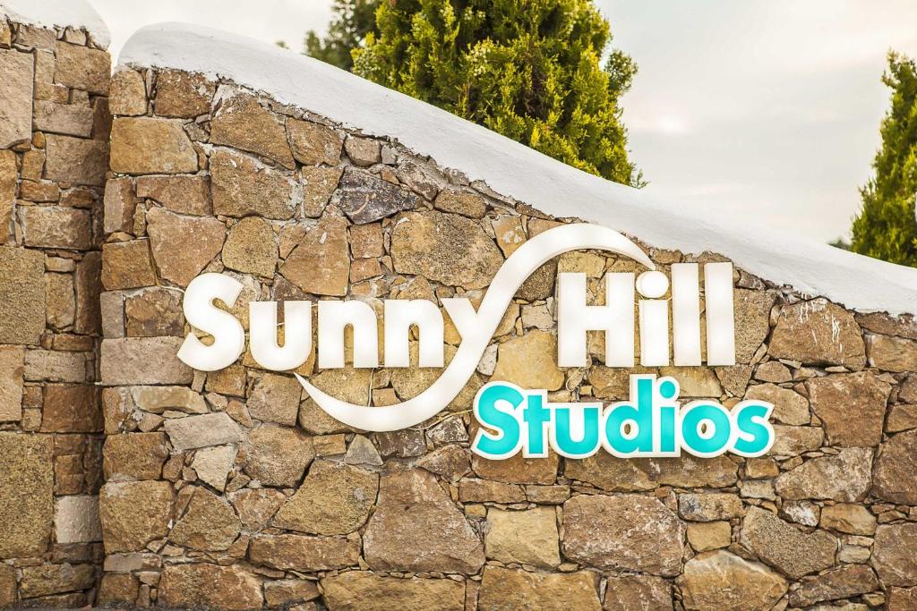 a sign for sunny hill studios on a stone wall at Sunny Hill in Sani Beach