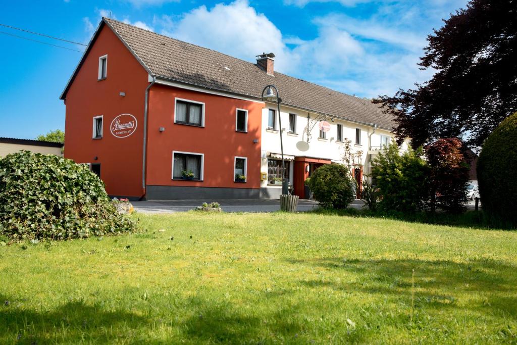 une maison rouge et blanche avec une cour verdoyante dans l'établissement Landgasthof Zur Erholung, à Breitscheid