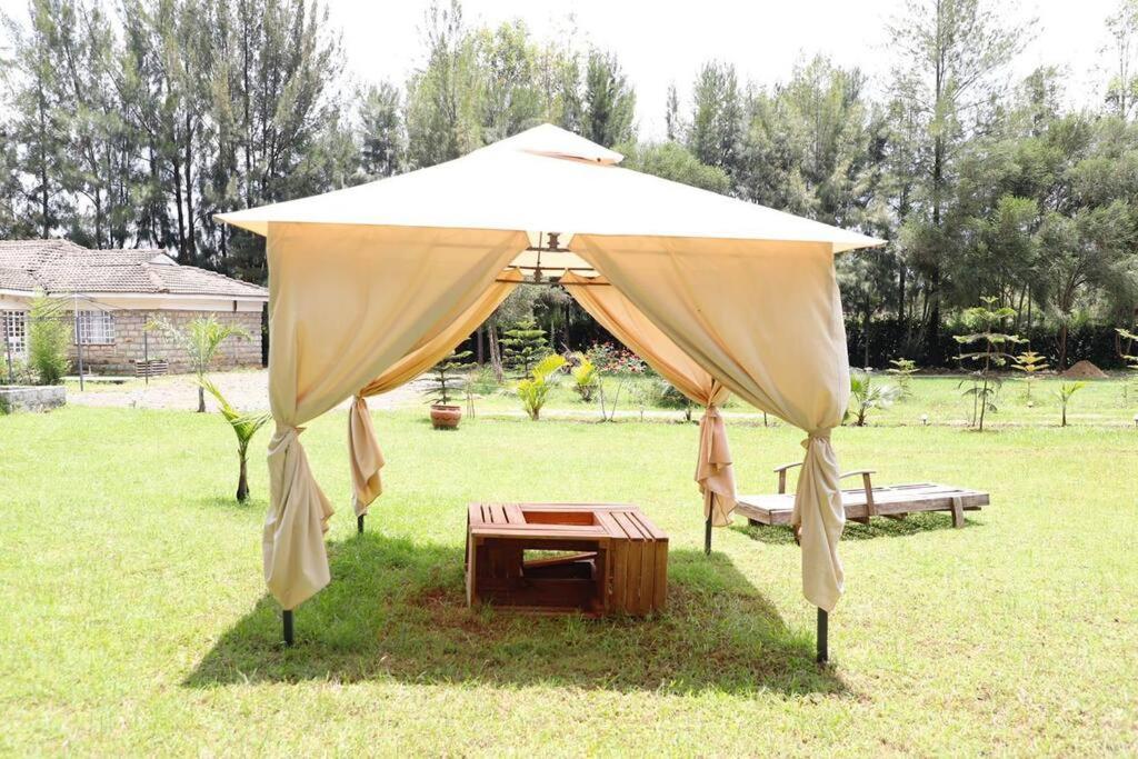 um grande guarda-chuva com uma mesa num campo em Win's Place em Eldoret