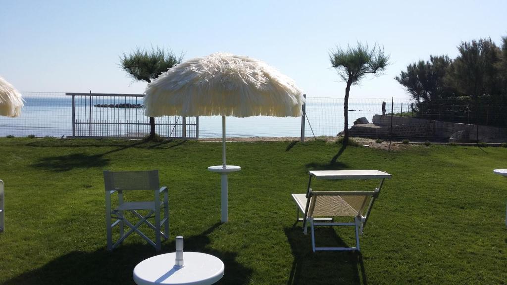 ein Tisch und zwei Stühle und ein Regenschirm auf dem Rasen in der Unterkunft Agriturismo Frontemare in Giulianova