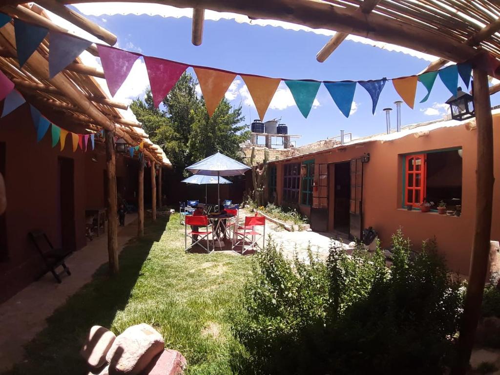 un patio con mesa, sillas y banderas en Humahuaca Hostel en Humahuaca