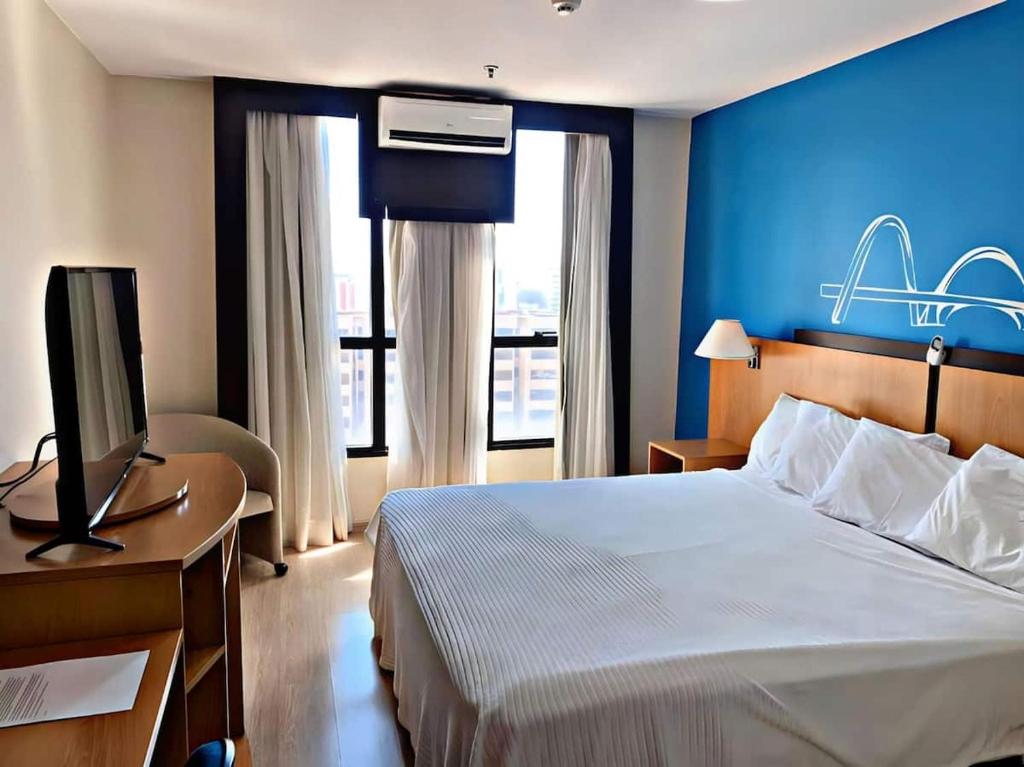 a hotel room with a bed with a blue wall at Lindo Flat 10° andar aconchegante em Brasilia in Brasilia