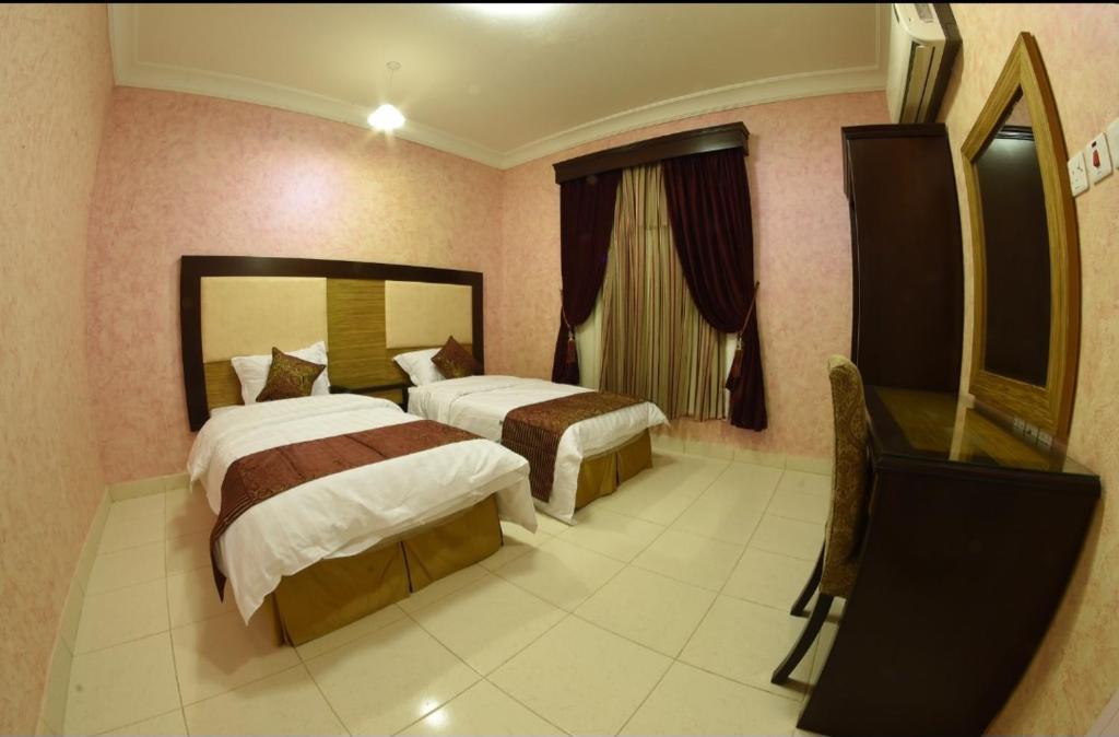 a hotel room with two beds and a mirror at شقق النخيل in Ar Rass