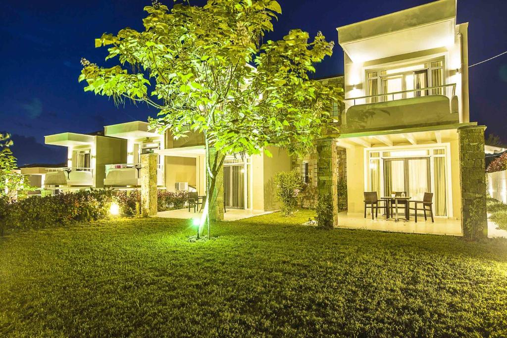 a house with a tree in the yard at night at Sunny Hill in Sani Beach
