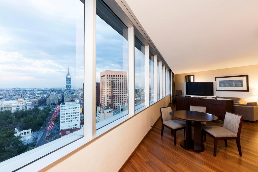 a room with a table and chairs and large windows at Hilton Mexico City Reforma in Mexico City