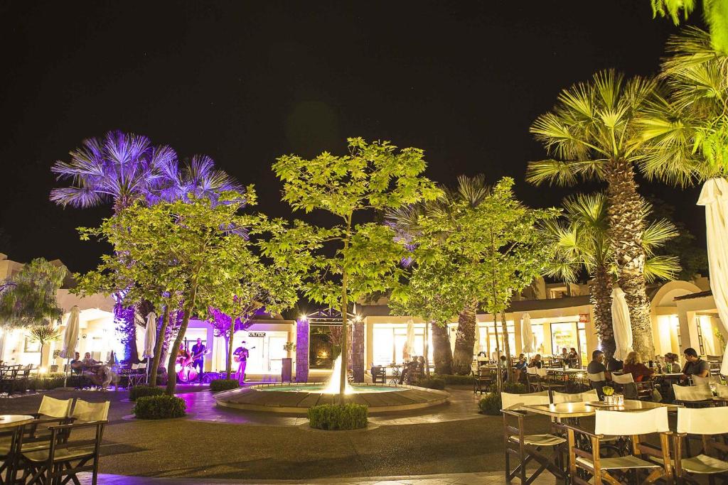 a restaurant with tables and chairs and palm trees at night at Sunny Hill in Sani Beach