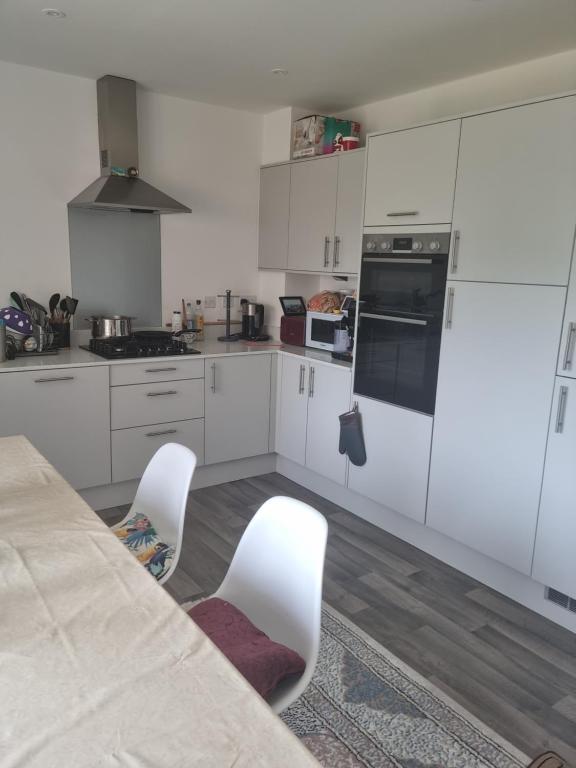 a kitchen with white cabinets and a table and chairs at Trundle bed- with office desk, small room in Newhaven