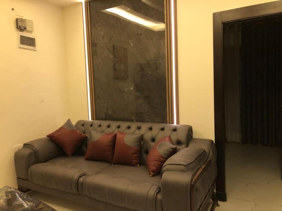 un sofá marrón con almohadas en la sala de estar en شقة فاخرة جديدة-غرفتين نوم وصالة صغيرة مع بلكونة Modern 2 Bedrooms Appartment with Balcony, en Amán