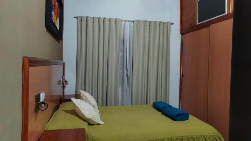 Un dormitorio con una cama verde y una ventana. en EL OASIS Habitaciones, en Córdoba