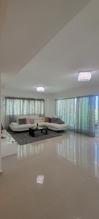 ein weißes Wohnzimmer mit 2 Betten und einem Tisch in der Unterkunft Lomar apartamento en Santo Domingo Este in Ensanche Los Minas