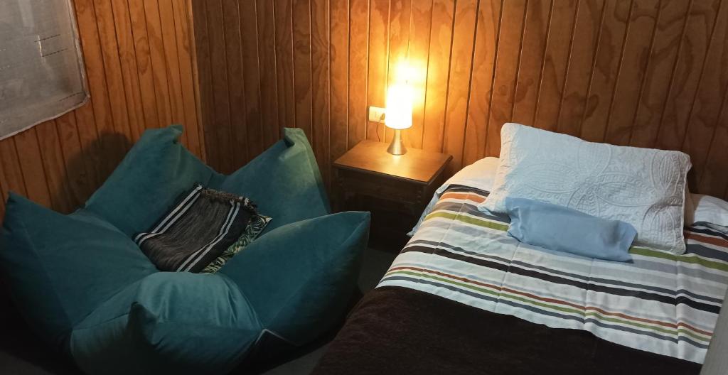 1 dormitorio con 1 cama y 1 silla junto a una lámpara en Casa Turística Arauco, en Arauco