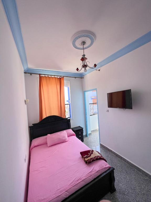 - une chambre avec un lit rose et une télévision à écran plat dans l'établissement Casa chaara, à Chefchaouen