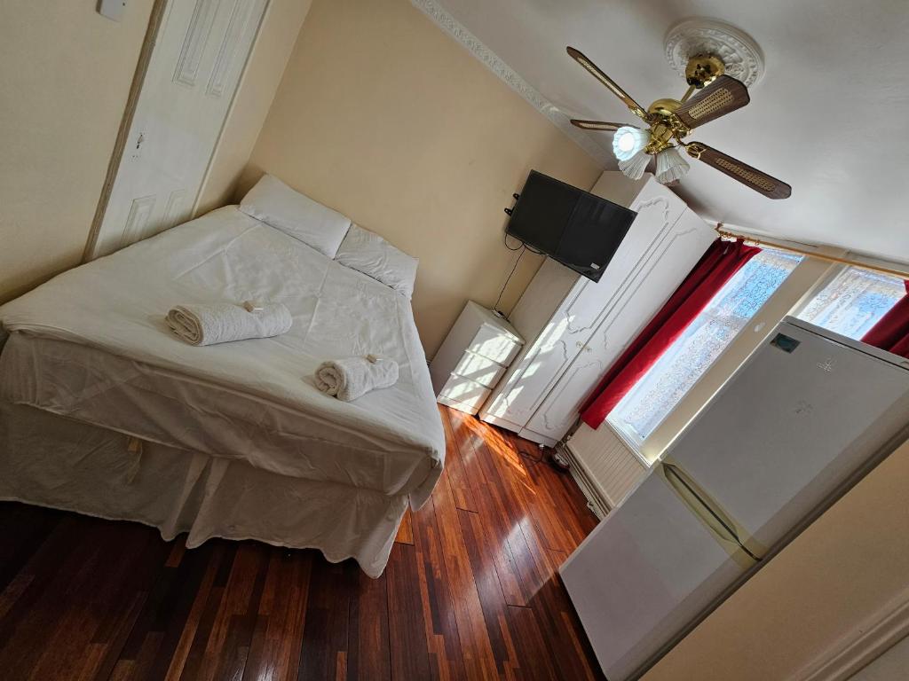 um pequeno quarto com uma cama e uma ventoinha de tecto em Silver rooms em Edmonton