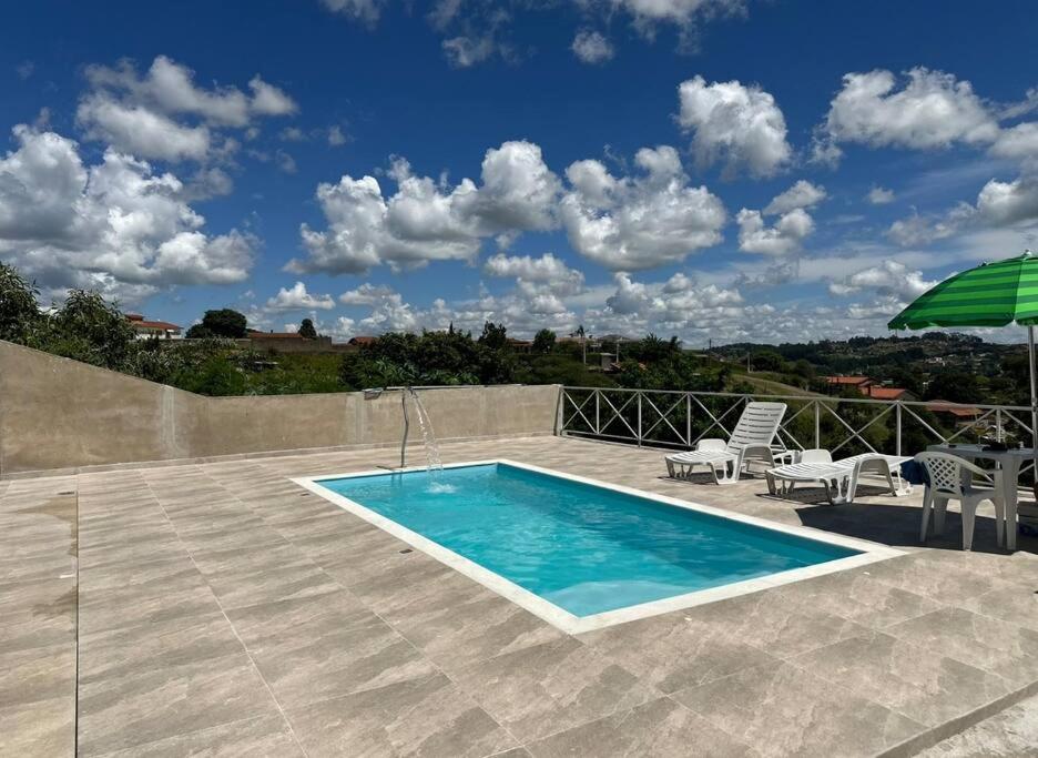 - une piscine avec des chaises et un parasol sur la terrasse dans l'établissement Chácara Por do Sol, à Serra Negra