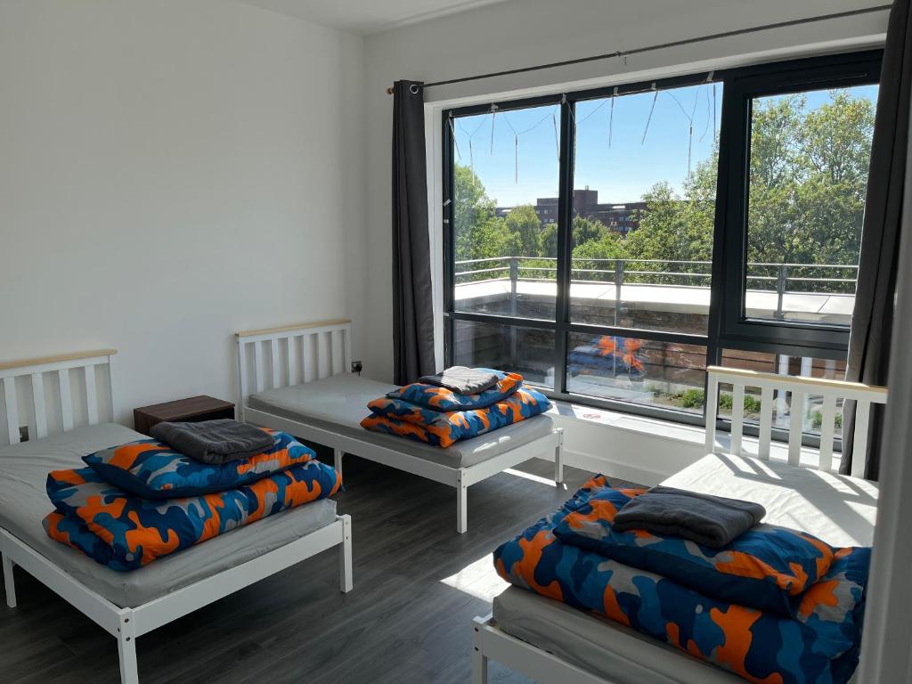 a room with three beds and a large window at Mordern Apartment in City Center in Manchester