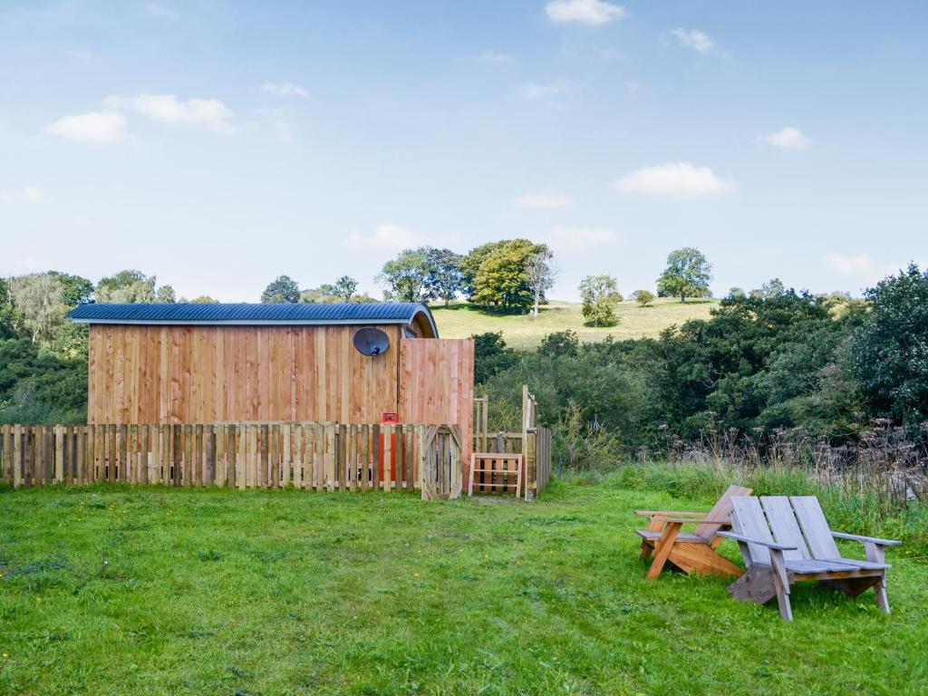 a wooden shed and a bench in a field at Partridge Hut-uk44850 in Walton