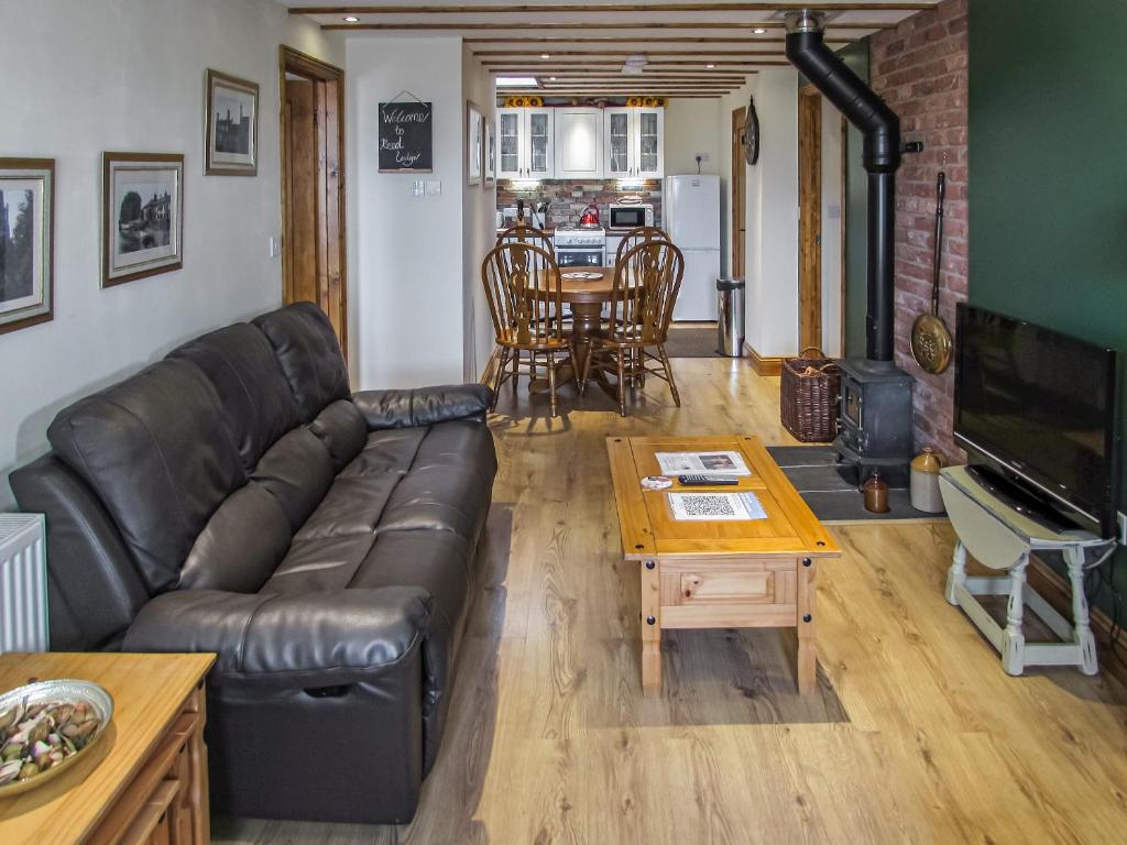 a living room with a leather couch and a table at Reed Lodge in Littleport