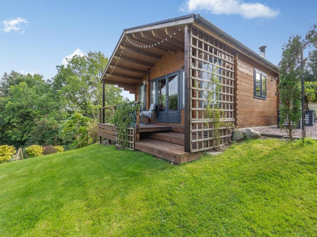 a small wooden cabin in a grassy yard at The Cabin Cefn Mawr in Highgate