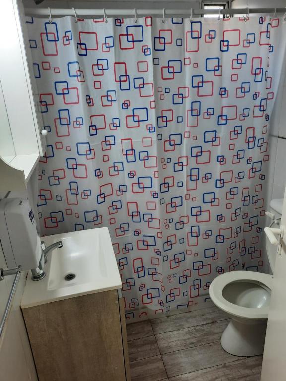 a bathroom with a shower curtain with a toilet and a sink at Depto céntrico de 3 habitaciones y cochera in Rosario