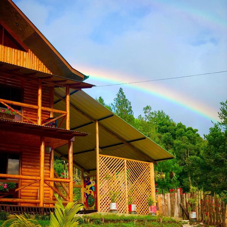 um arco-íris no céu acima de uma casa de madeira em Treff Lodge Hotel em Oxapampa