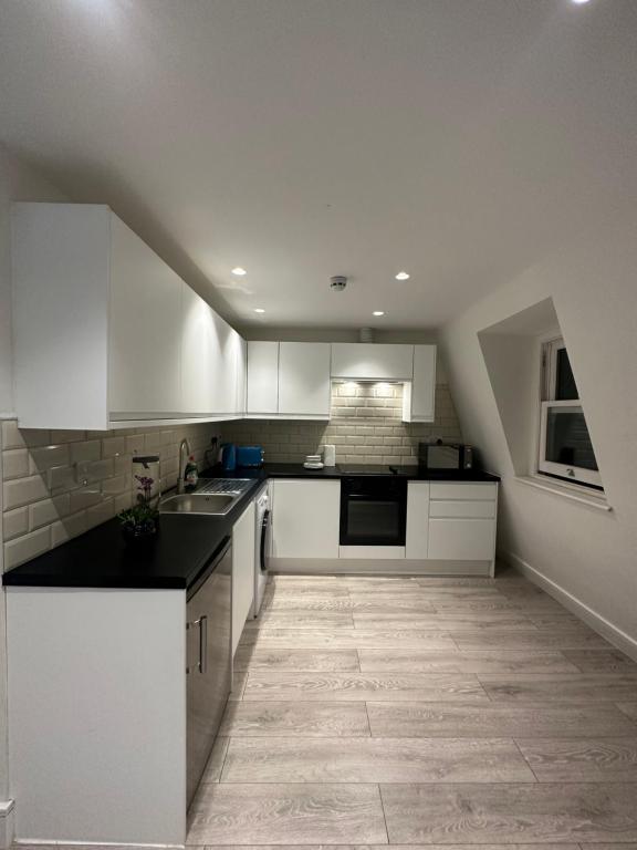 a kitchen with white cabinets and a tile floor at Home-like 1-BR flat in Victoria in London