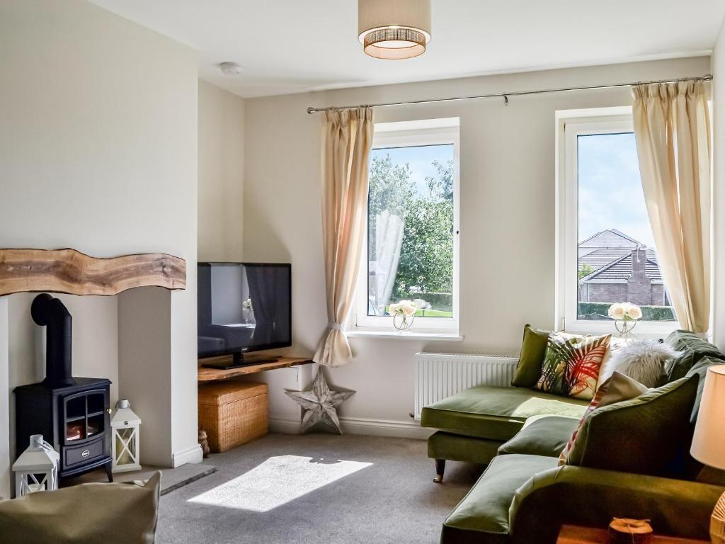 sala de estar con sofá verde y TV en Southways Cottage, en Cumwhinton