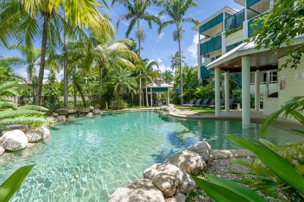 a swimming pool in front of a building with palm trees at Verandahs Boutique Apartments in Port Douglas