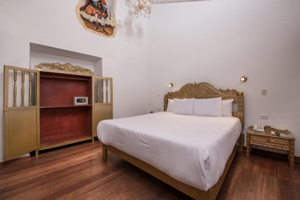 a bedroom with a large white bed and wooden floors at Inkarri Regocijo Plaza in Cusco