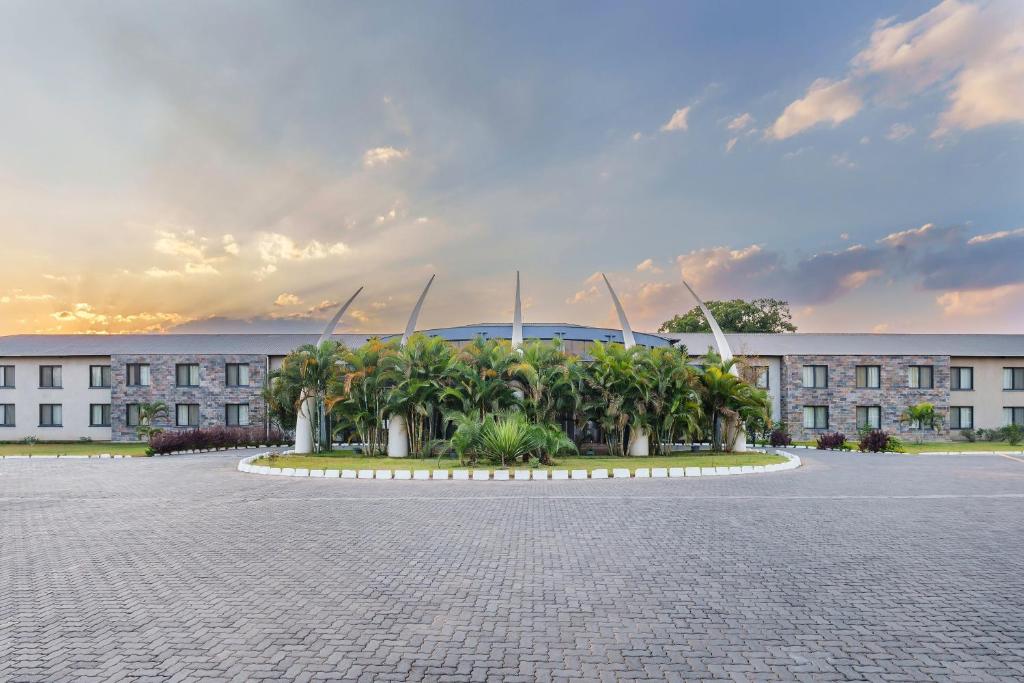 ein Gebäude mit vielen Palmen davor in der Unterkunft Protea Hotel by Marriott Ndola in Ndola