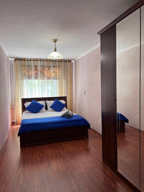 um quarto com uma cama com almofadas azuis e uma janela em Уютные апартаменты em Shymkent