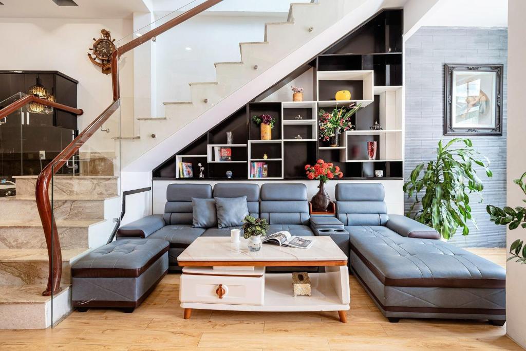 a living room with a blue couch and a staircase at Villa Hẻm Đà Lạt in Da Lat