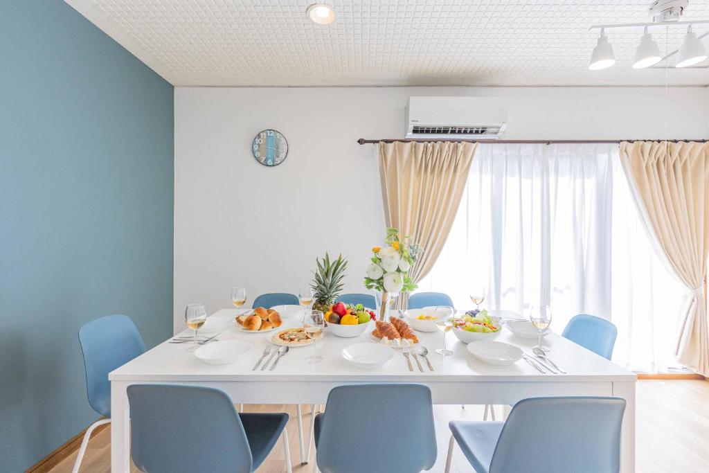Azami Ann Maisonette في شيراهاما: غرفة طعام مع طاولة بيضاء وكراسي زرقاء
