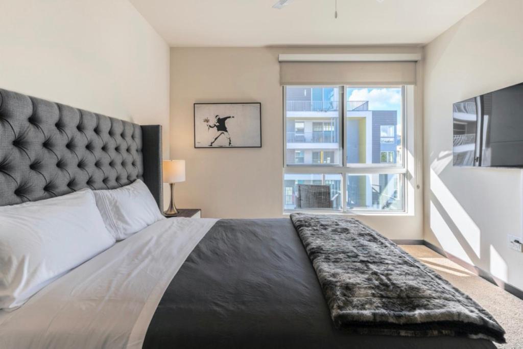 a bedroom with a large bed with a large window at New WeHo Luxury Apartment in Los Angeles