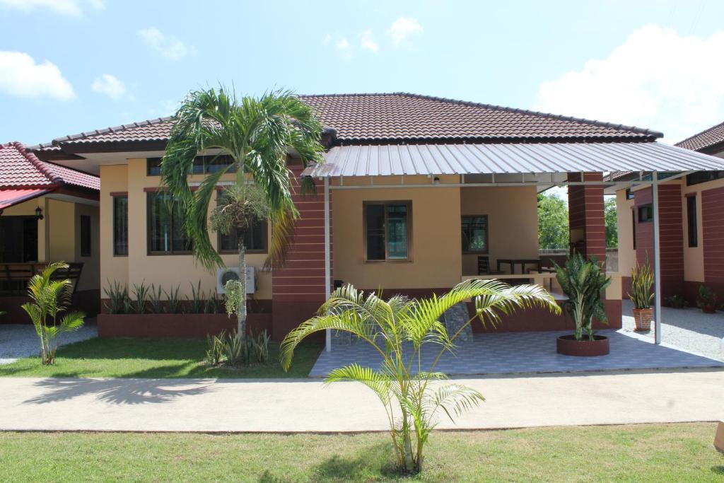 une maison avec des palmiers devant elle dans l'établissement Naluemon Village FH 3-4, à Ban Phe