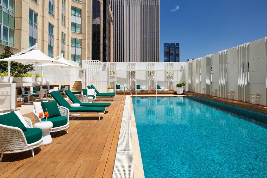 a pool on the rooftop of a hotel with lounge chairs at Swissotel Sydney in Sydney