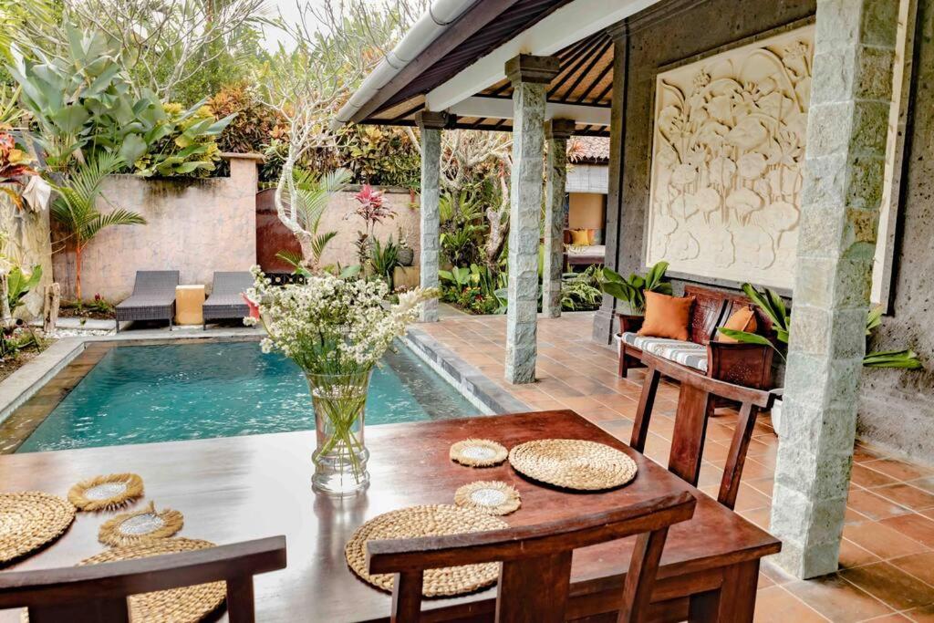 eine Terrasse mit einem Tisch, Stühlen und einem Pool in der Unterkunft Cultural Gem: 2bd Private Villa in Ubud