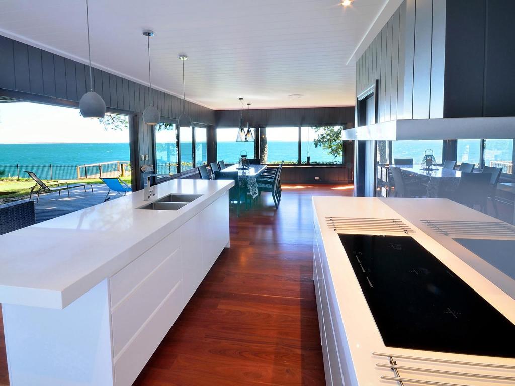 uma cozinha com balcões brancos e vista para o oceano em Dolphins at Sunset em Amity Point