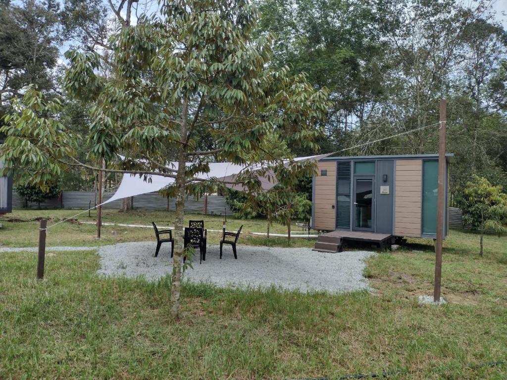 a tiny house with two chairs and a table at Sungai Tiny House 2 in Raub