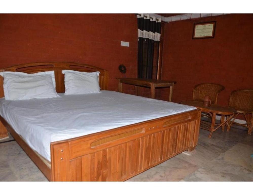 a bedroom with a wooden bed with white sheets at Rekha & Kamla Homestay, Orchha 