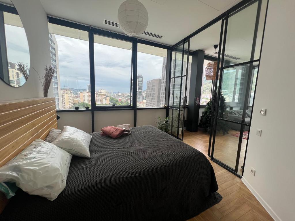 ein Schlafzimmer mit einem großen Bett und großen Fenstern in der Unterkunft Axis Towers 1 bedroom 4 guests! in Tbilisi City