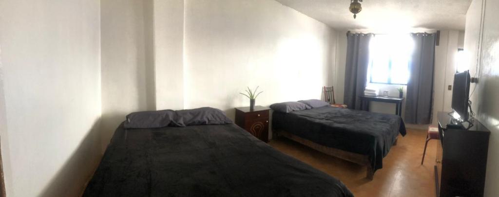 1 dormitorio con 2 camas y TV. en Hotelito Ejido de la 10 en Puebla