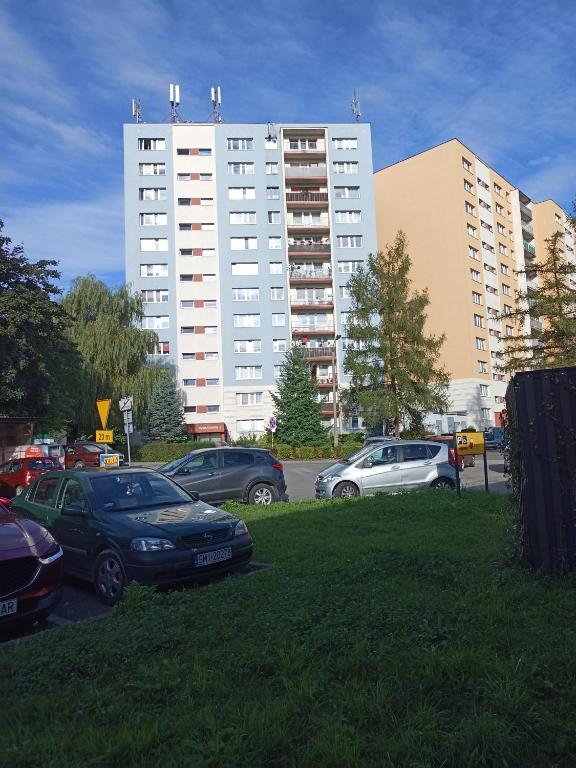 a parking lot with cars parked in front of a building at Apartament Gliwice in Gliwice