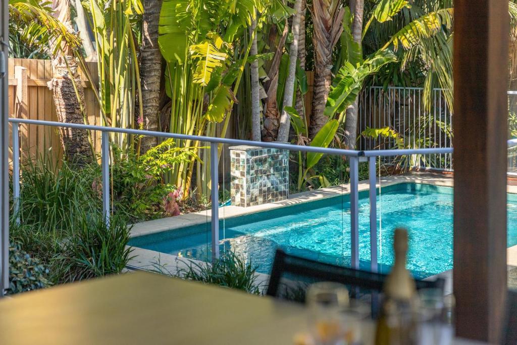 a swimming pool in a garden with a table at Lazuli in Blueys Beach