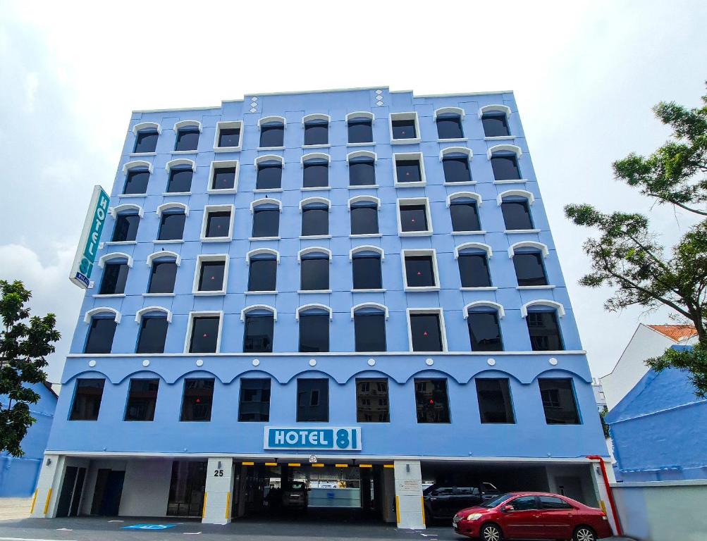Hotel 81 Palace - NEWLY RENOVATED في سنغافورة: مبنى الفندق الأزرق مع سيارة حمراء متوقفة في الأمام