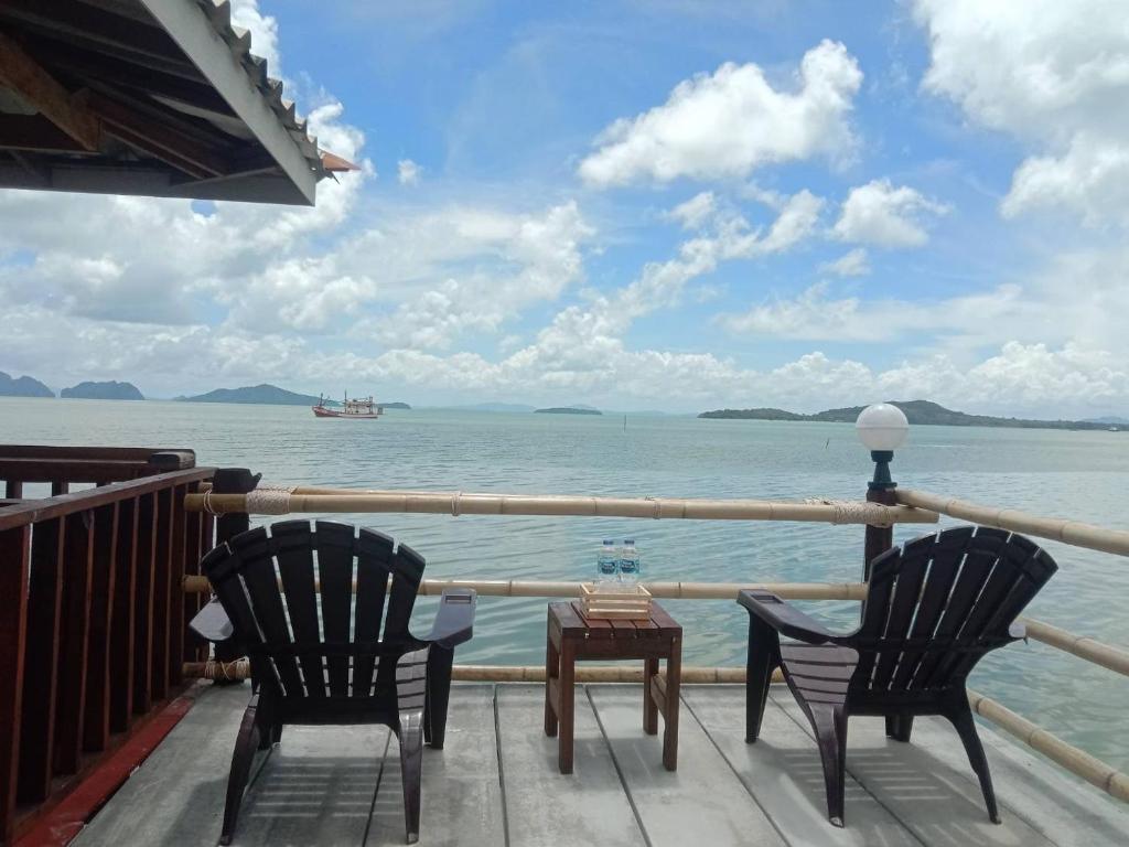 2 Stühle und ein Tisch auf einer Terrasse mit Blick über das Wasser in der Unterkunft Navareeya House Seaview in Ko Lanta