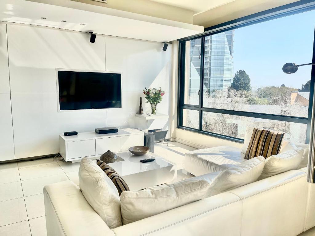 Johannesburg的住宿－Stunning 2 Bedroom Apartment，客厅配有白色沙发和大窗户
