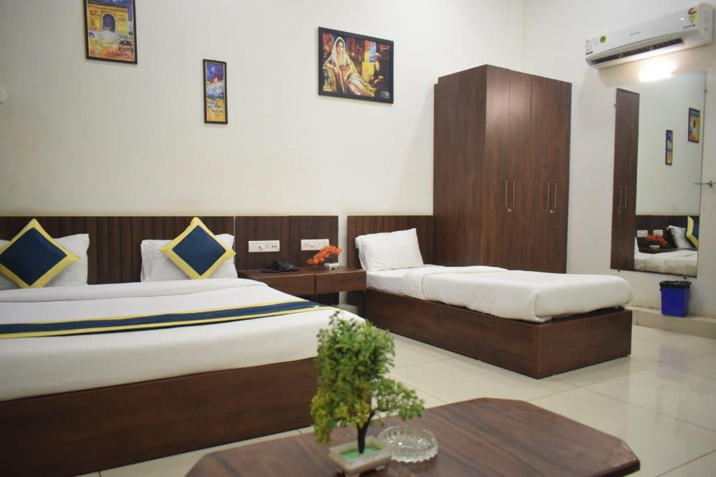 a hotel room with two beds and a table at Hotel Lakshya Sheesh Mahal Indore in Indore